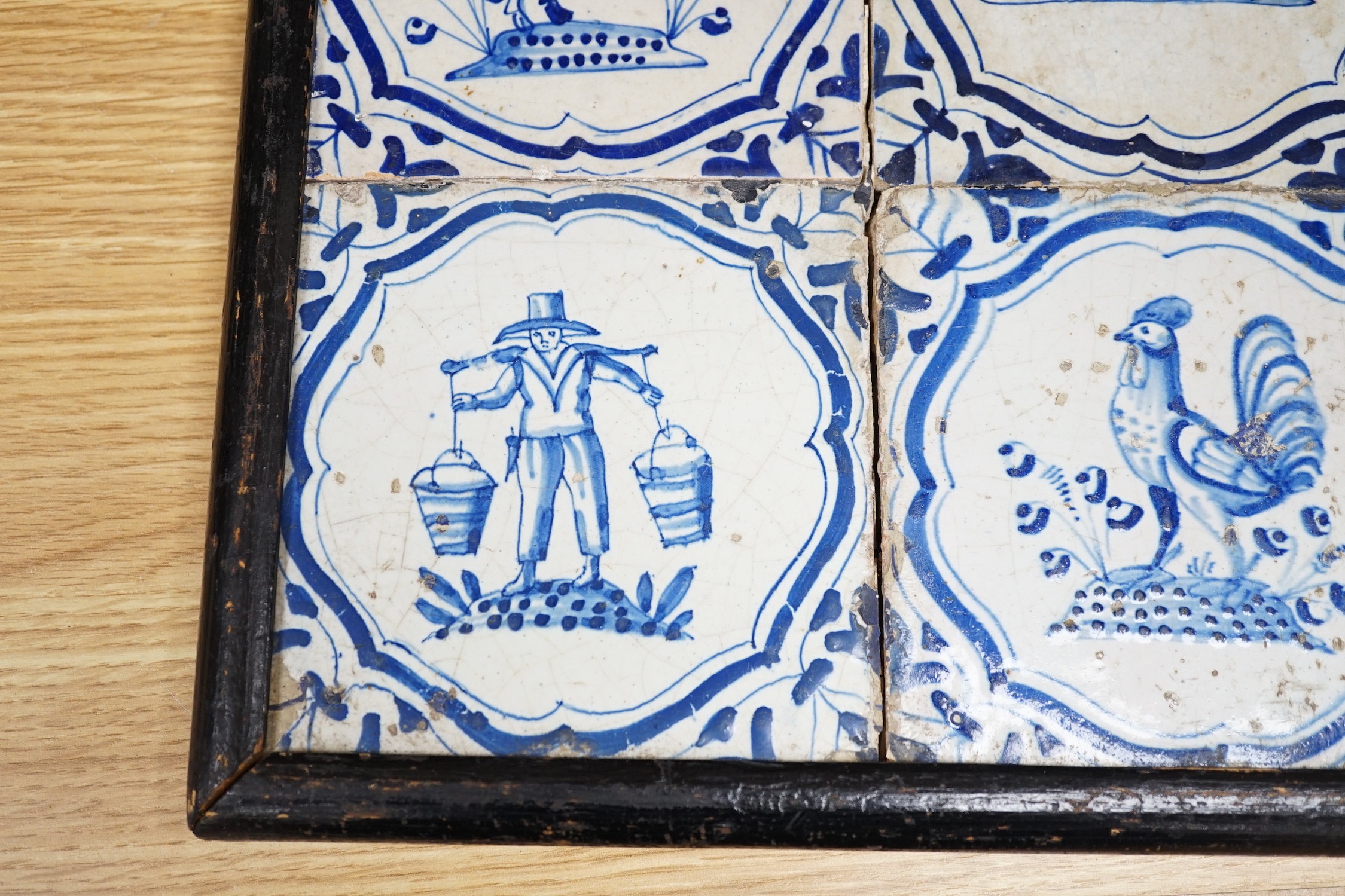 Four 17th century Dutch Delft blue and white tiles, decorated with deer, cockerels and figures within shaped panels (frame 29cm)